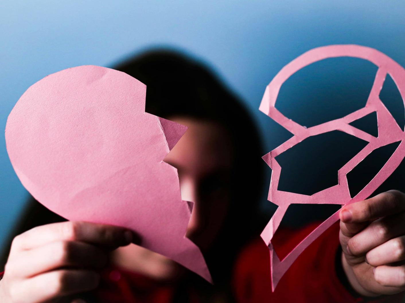 Woman holding two parts of a paper heart