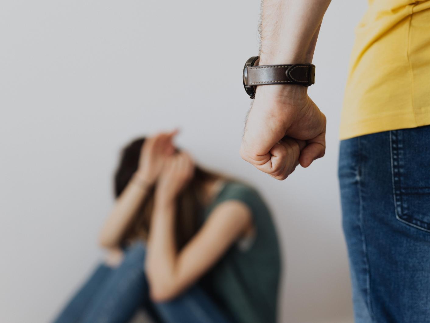 Photo of a man clenching his fist near a woman covering her face